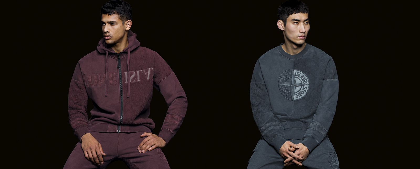 One model in a maroon, hooded sweater and matching pants, and one in a blue sweater and matching pants.
