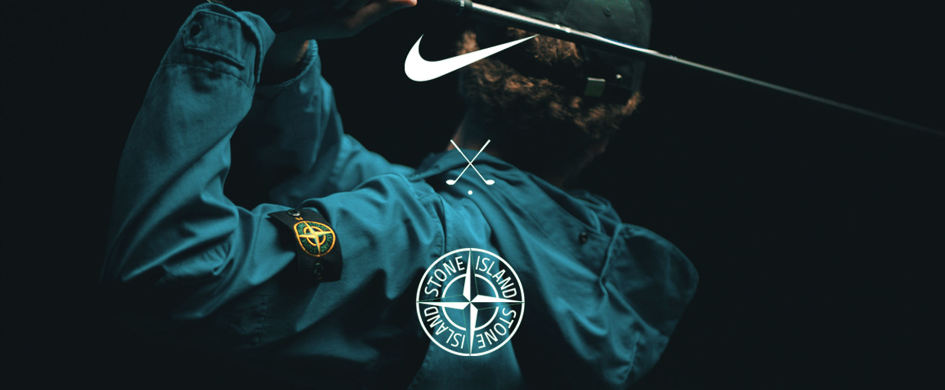 Back view of model swinging golf club wearing a turquoise, performance jacket with the Stone Island badge on left arm.