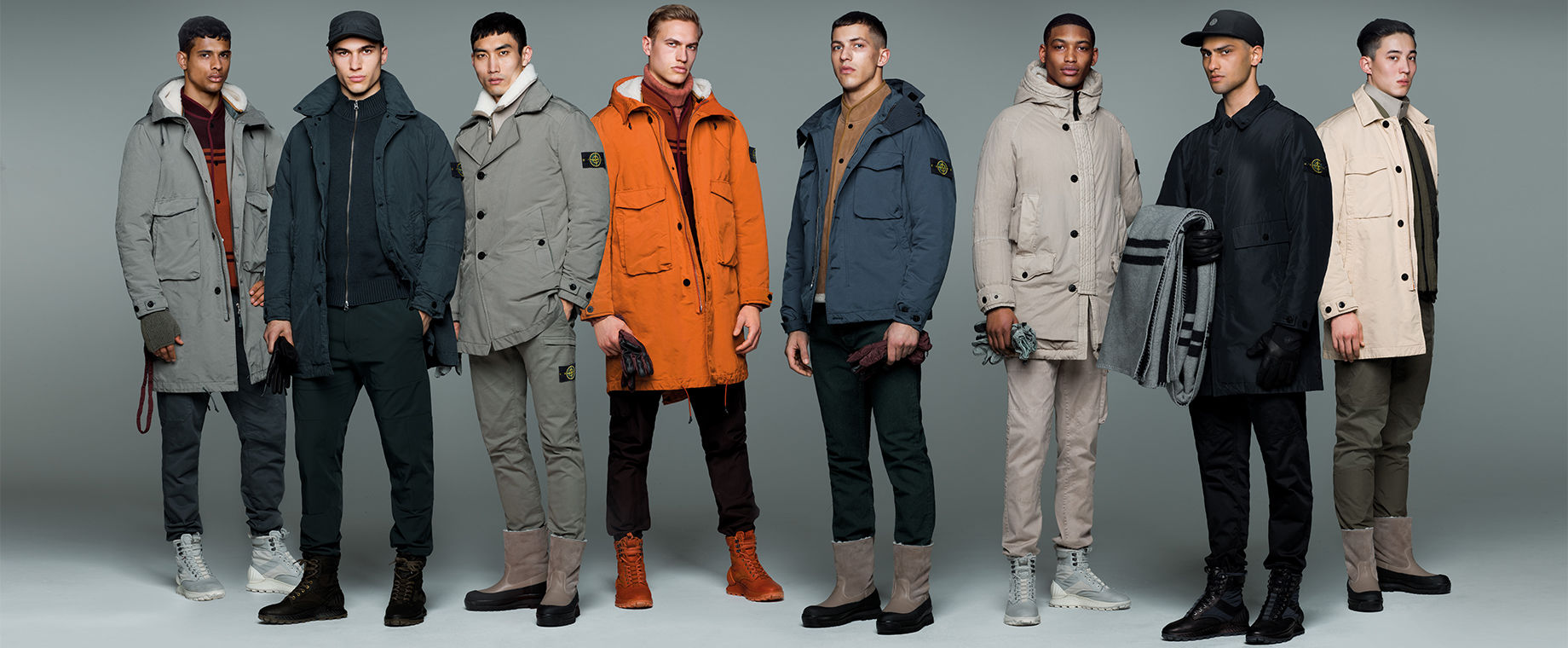 Eight models wearing Stone Island jackets, pants and caps in different styles and colors.