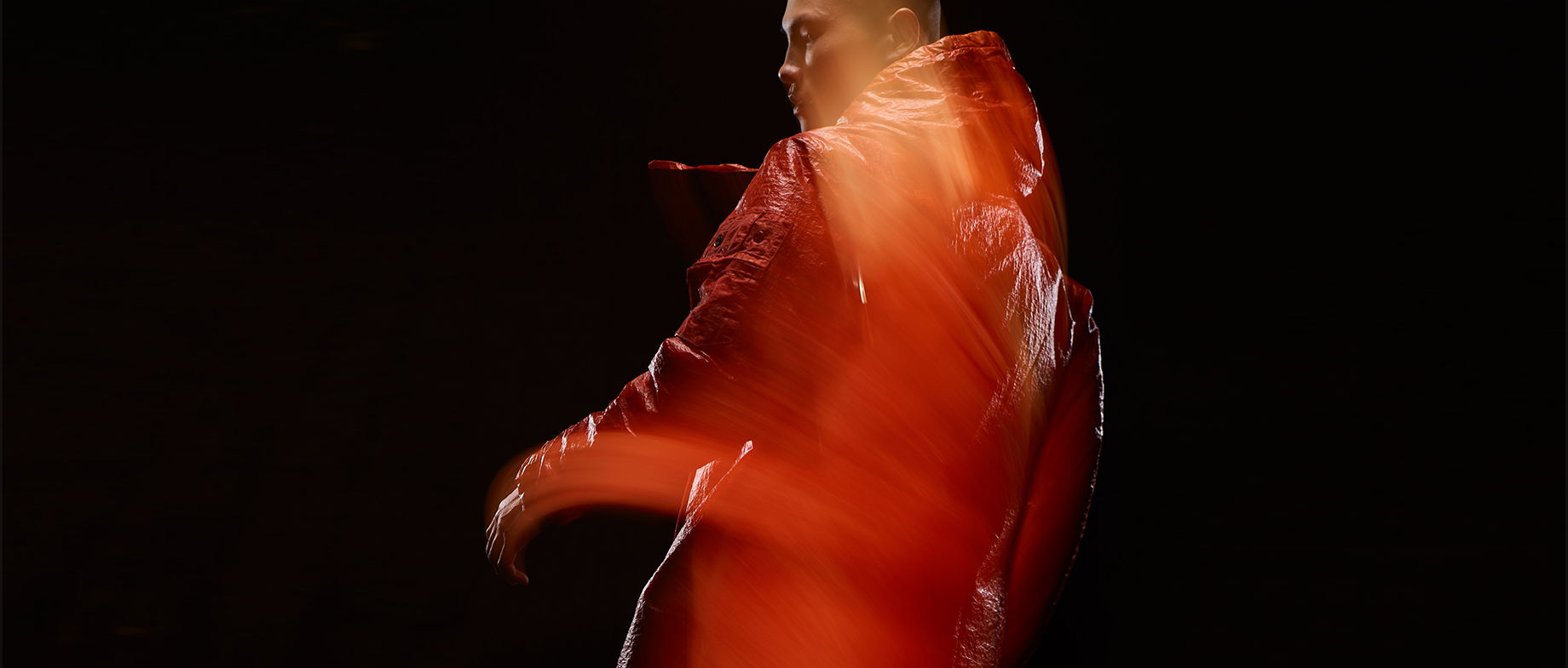 Blurred shot of model wearing red, hooded jacket.
