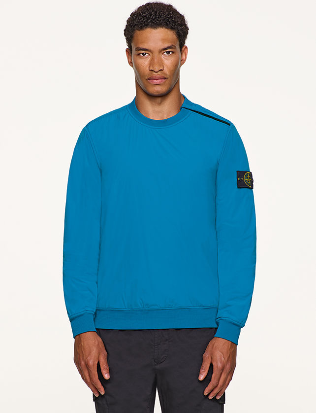 Model wearing turquoise, performance crewneck top with Stone Island badge on left arm.