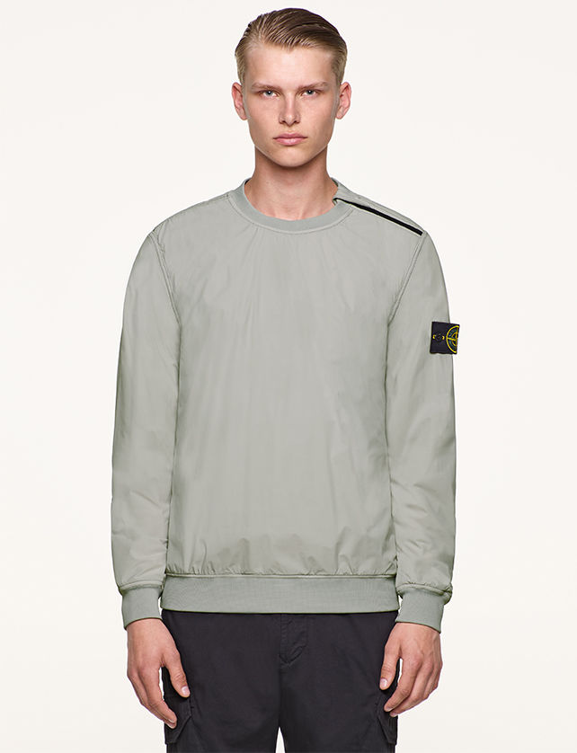 Model wearing gray, performance crewneck top with Stone Island badge on left arm.