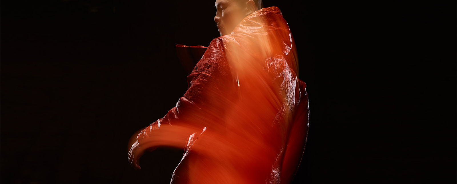Blurred shot of model wearing red, hooded jacket.