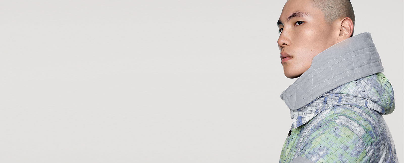 Model wearing hooded jacket with graphic design print and oversized gray collar.