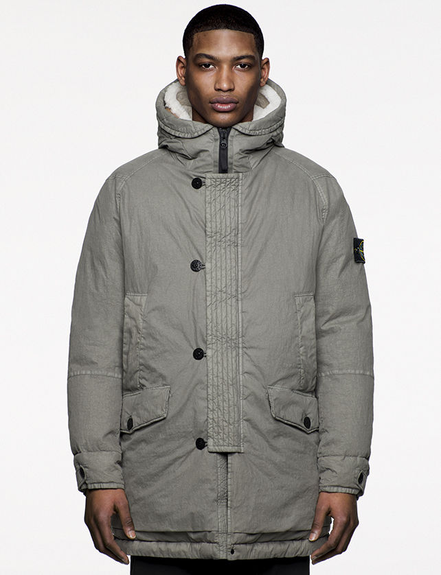 Model wearing gray, hooded, quilted jacket with flap and snap horizontal pockets, vertical welt pockets at chest and zipper and button fastening.