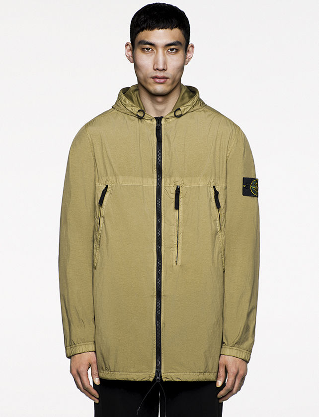 Model wearing light green jacket with two diagonal zipper pockets at chest and one vertical one at center left and zipper closure.
