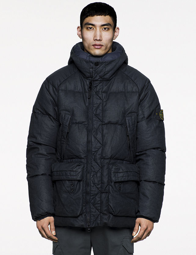 Model wearing oversized, navy, quilted jacket with chimney collar, four pockets and off center zipper closure.