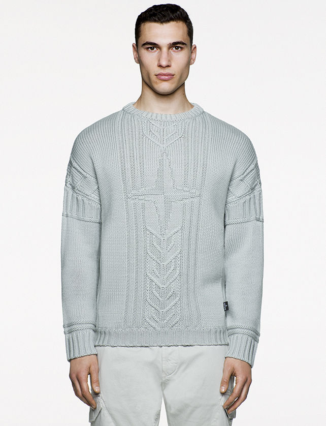 Model wearing gray knitted sweater with Stone Island logo at chest.