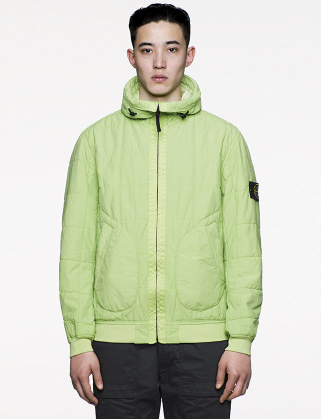 Model wearing green, quilted bomber jacket with stand up collar, diagonal pockets and zipper fastening.