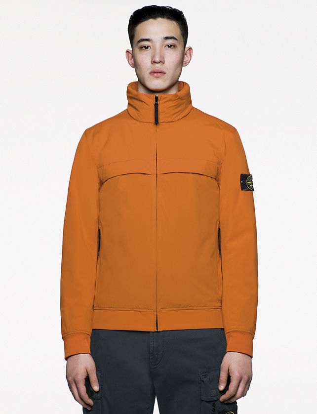 Model wearing casual, orange jacket with chimney collar zipped up to chin.