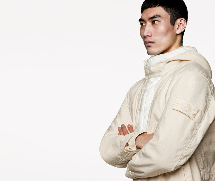 Model wearing white hooded jacket with white ghost badge on left arm.