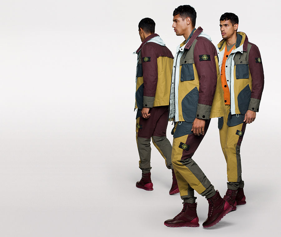 Model wearing multi colored jacket with large diagonal bellows pockets and matching pants.