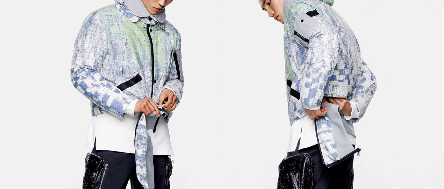 Two models wearing the same multi colored jacket with graphic print and black zipper fastening.