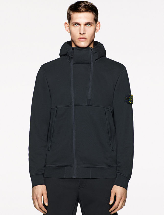 Model wearing a black sweater jacket with a stand collar, dual zipper closure, and Stone Island badge on the left arm