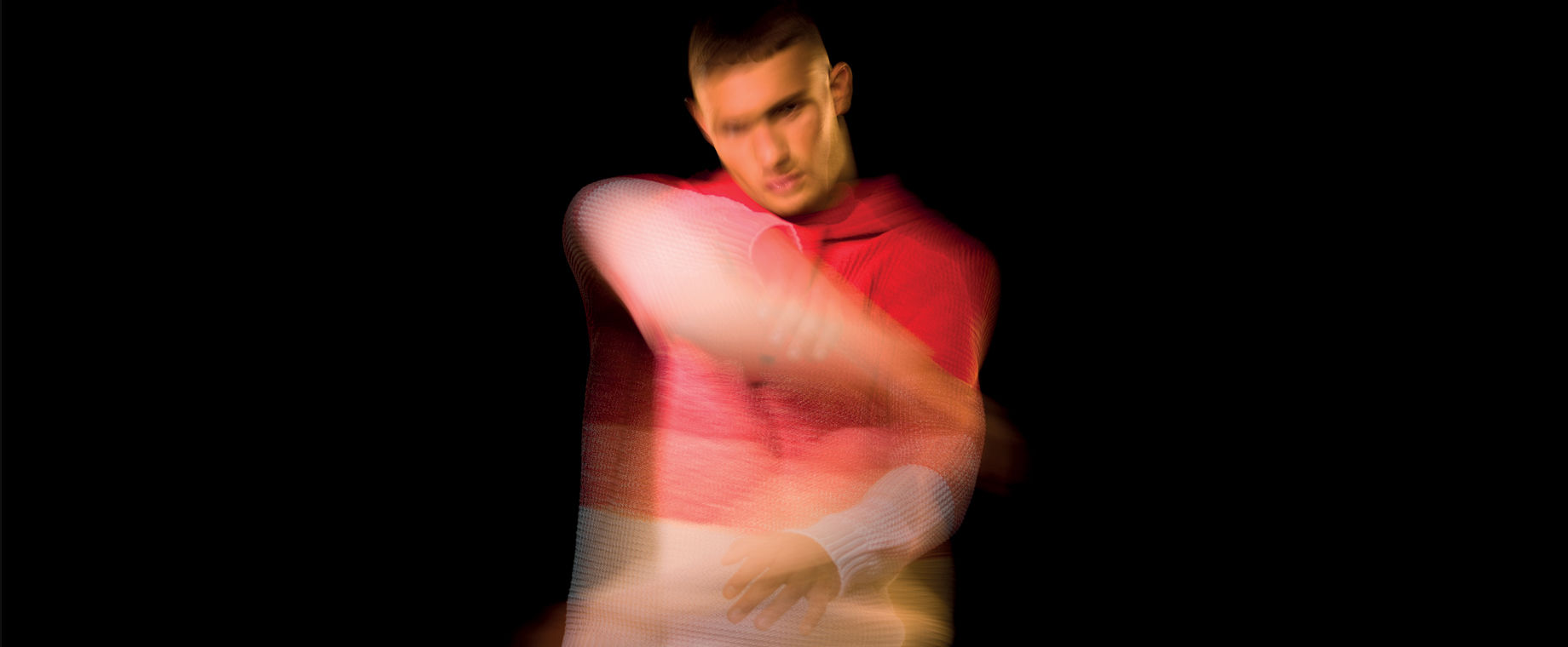 Blurred image of model wearing a sweater with red to white gradient stripes.
