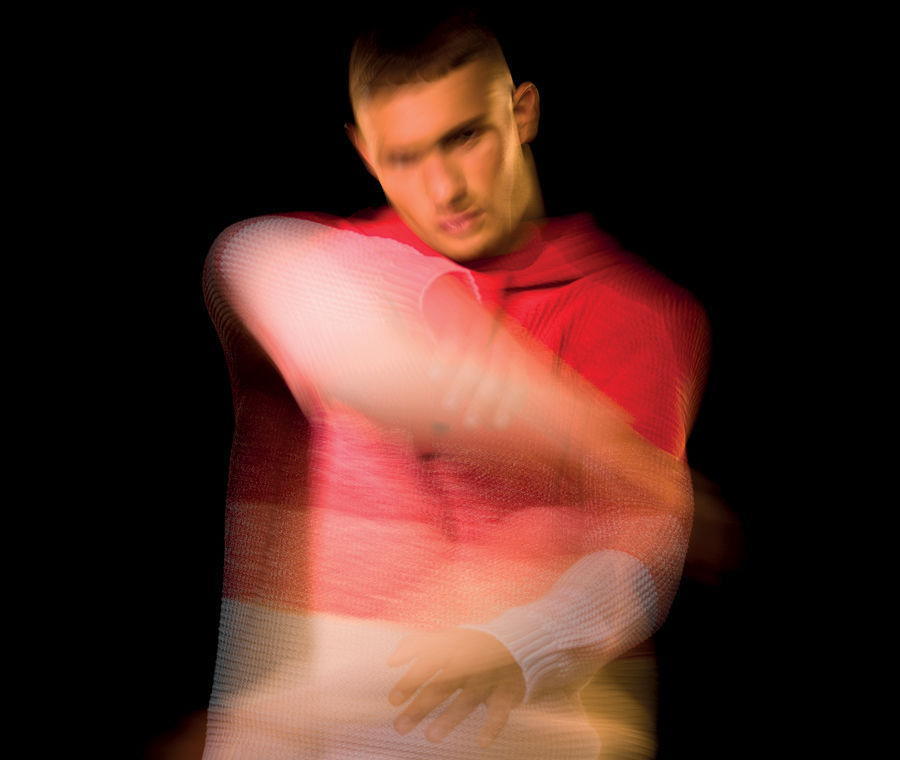 Blurred image of model wearing a sweater with red to white gradient stripes.