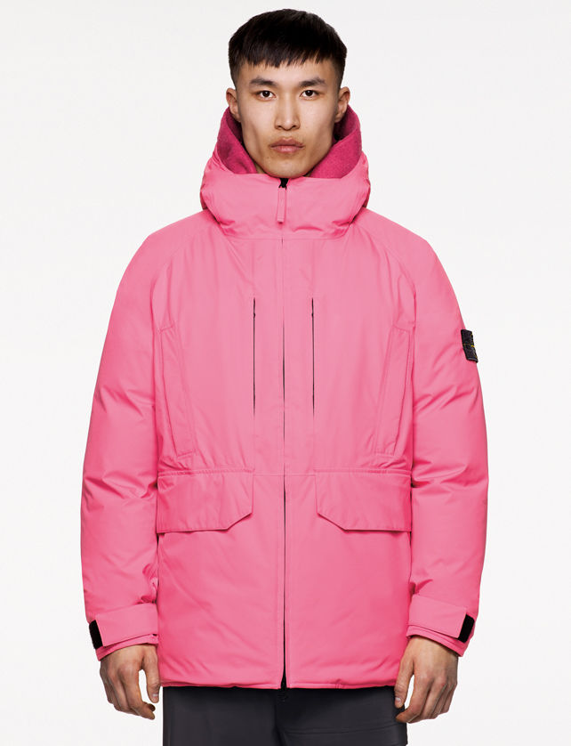 Model wearing dark colored pants and a pink hooded jacket with standing collar, zipper fastening, welt chest pockets, hand pockets with flap and strap at cuffs.