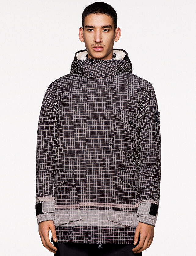 Model wearing black pants and a black check print jacket with hood, collar with two snap fastening, hidden zipper closure and light gray colored cuffs and lower waistline.