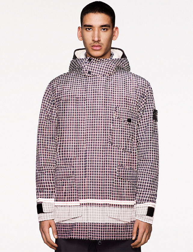 Model wearing black pants and a dark colored check print jacket with hood, collar with two snap fastening, hidden zipper closure and light off white colored cuffs and lower waistline.