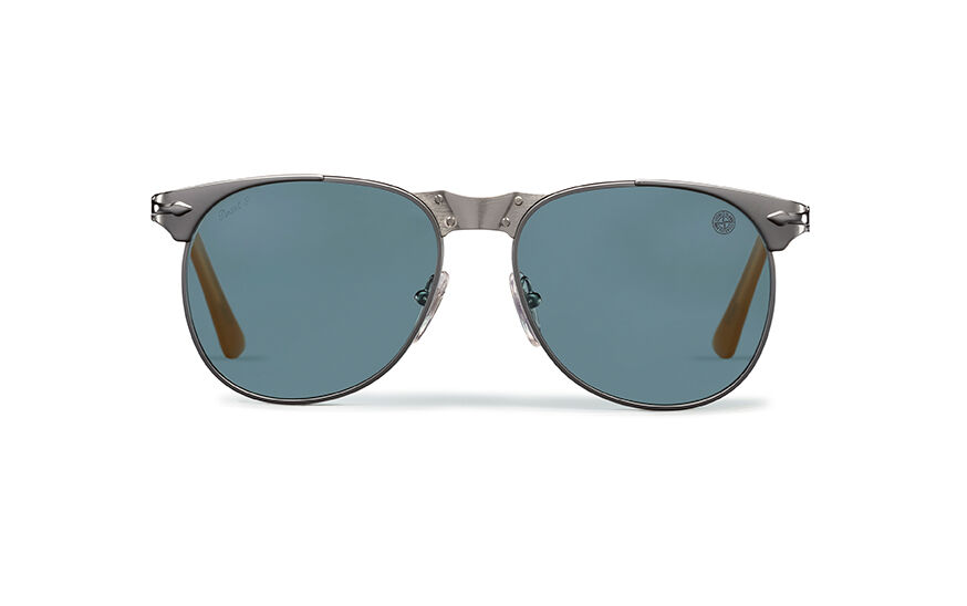 Still life image of a pair of sunglasses with gray metal frame, drop shape lenses, a large metal bridge with tiny screws, adjustable nosepads and dark orange acetate temple tips.