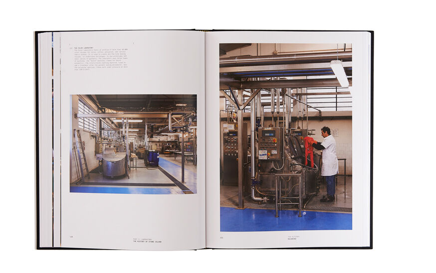 Still life image of an open hardcover book showing printed text and a picture of the interior of a factory on the left page and a man working on a machine in the factory on the right page.