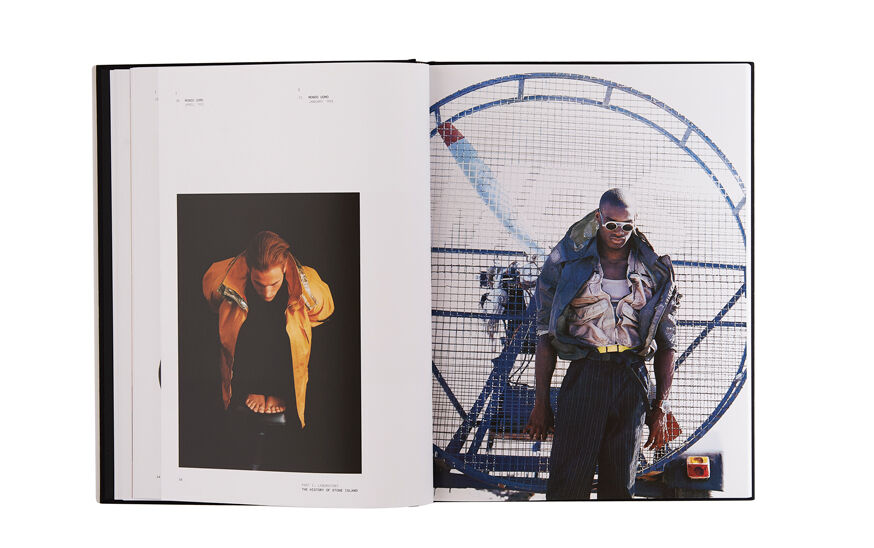 Still life image of an open hardcover book showing a picture of a model in a yellow jacket on the left page and a model wearing pinstriped pants and a khaki jacket on the right page.