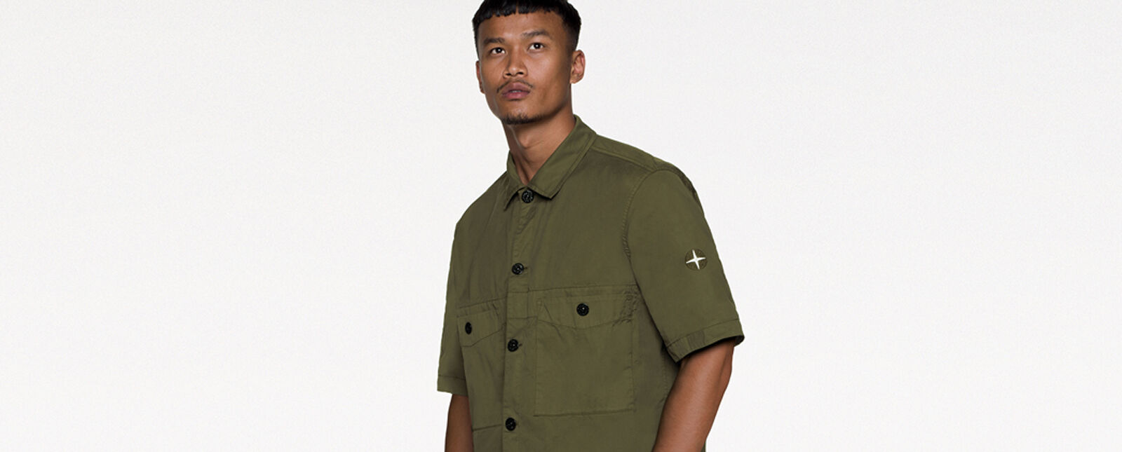 Model wearing a military green short sleeved shirt with button fastening, two patch pockets with snap fastening on the chest and the two tone Stone Island Compass logo embroidery on the left sleeve.