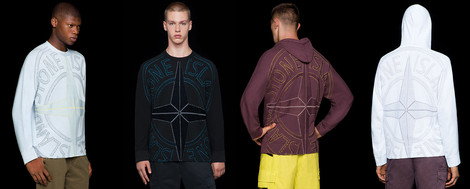 Four models wearing pants in different styles and colors, two of them wearing a crewneck t shirt with long sleeves and a large Stone Island compass rose logo embroidery on the front, the other two showing the same embroidery on the back of hooded sweatshi