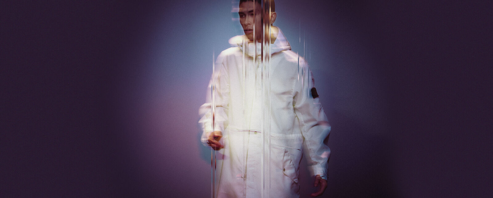 View of a model wearing a white parka with Stone Island Shadow Project badge on the upper left sleeve.