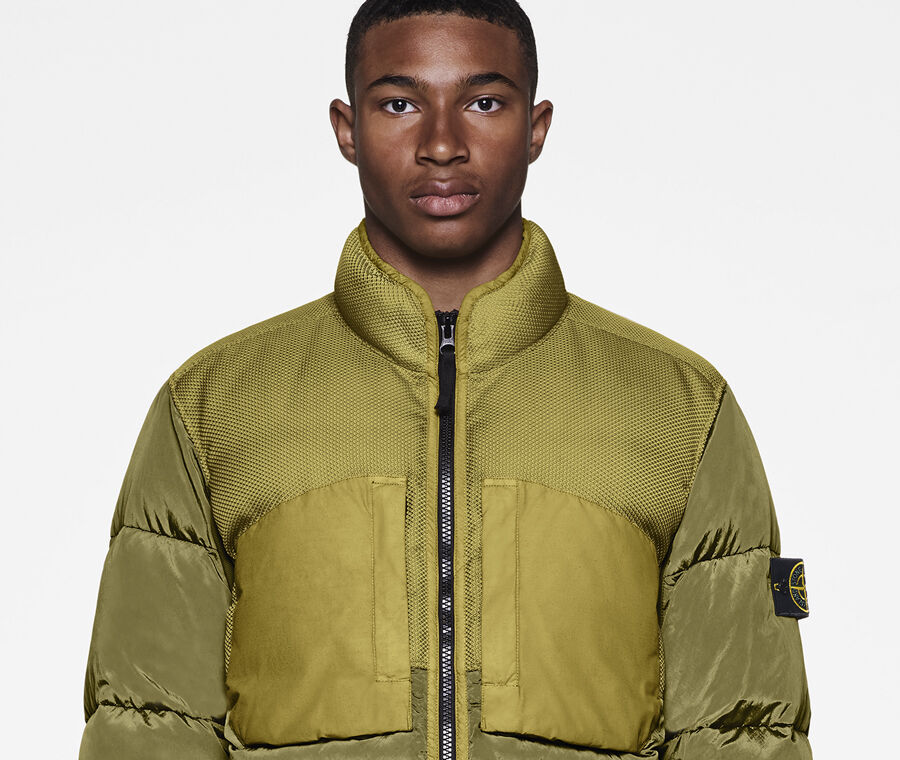 Model wearing military green cargo pants and a khaki down jacket with standing collar, two way zipper fastening and elasticated cuffs.