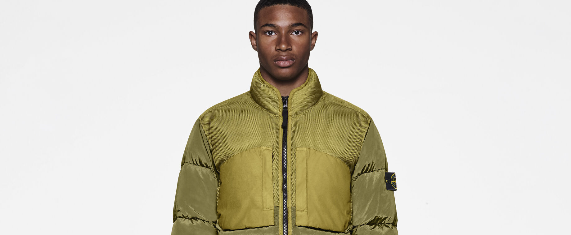 Model wearing military green cargo pants and a khaki down jacket with standing collar, two way zipper fastening and elasticated cuffs.