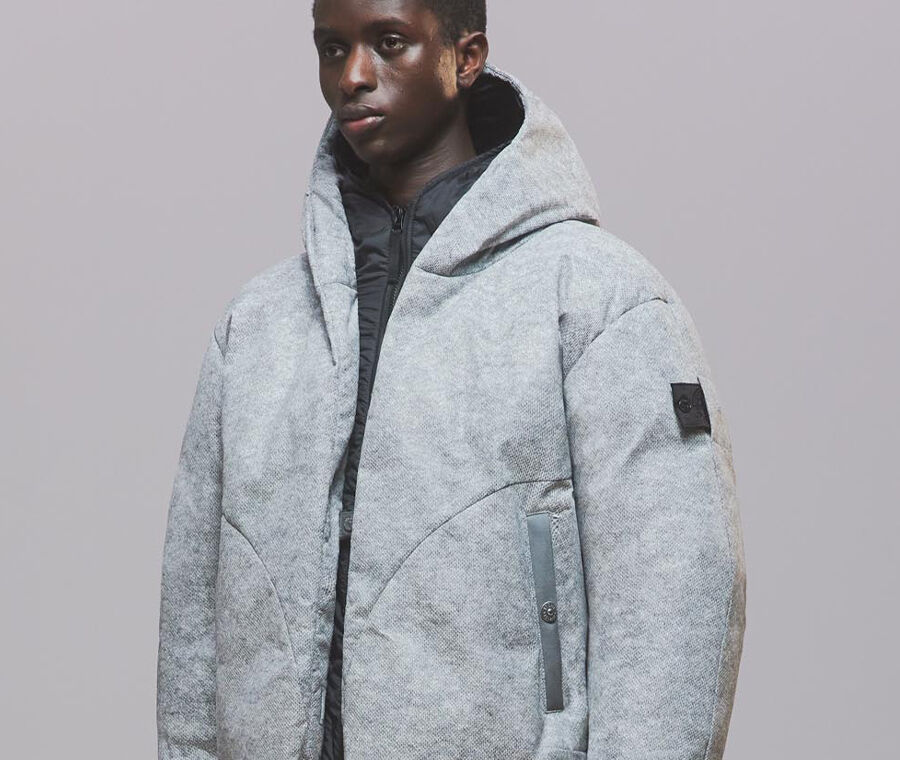 Model wearing a gray hooded jacket with Shadow Project badge on sleeve.
